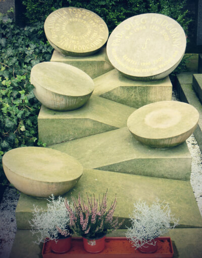 a photograph of a stone memorial in Prague. Five bowls balance on zig zag levels.